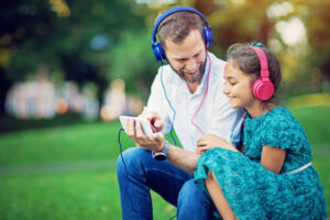 Father and daughter are listening the music in park